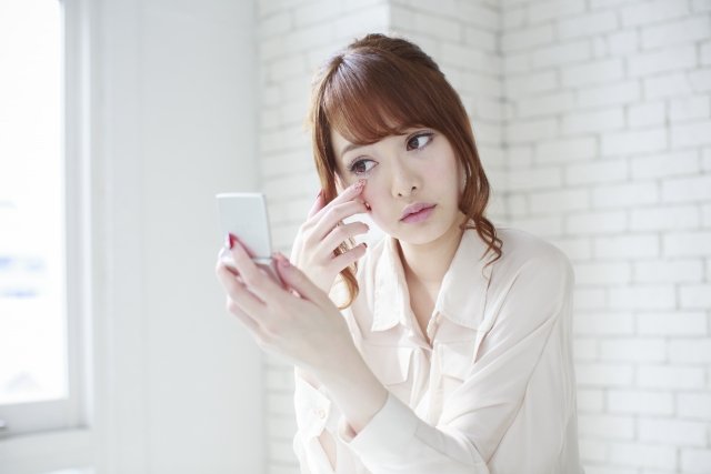 鏡で目元見る女性