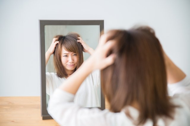 鏡と頭を抱える女性