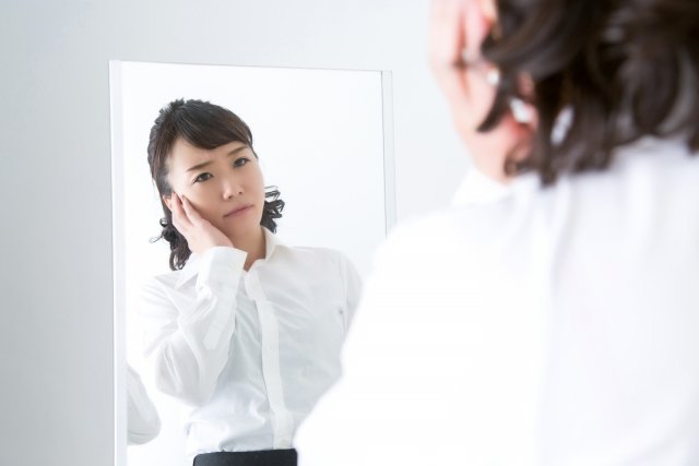 鏡を見て考える女性